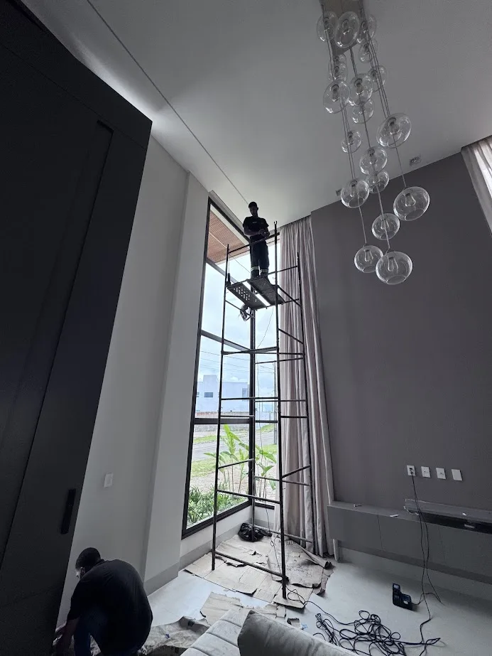 Equipe SEG instalando lustre no pé-direito duplo da residência